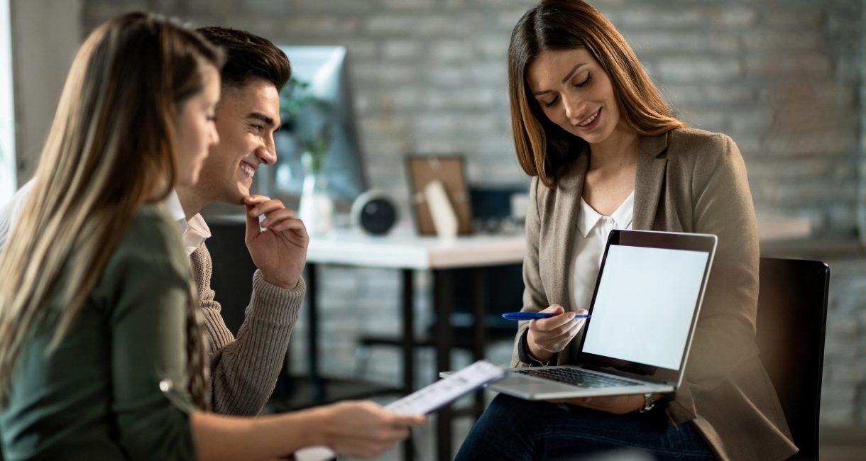 Happy couple and their insurance agent using laptop on a meeting in the office.